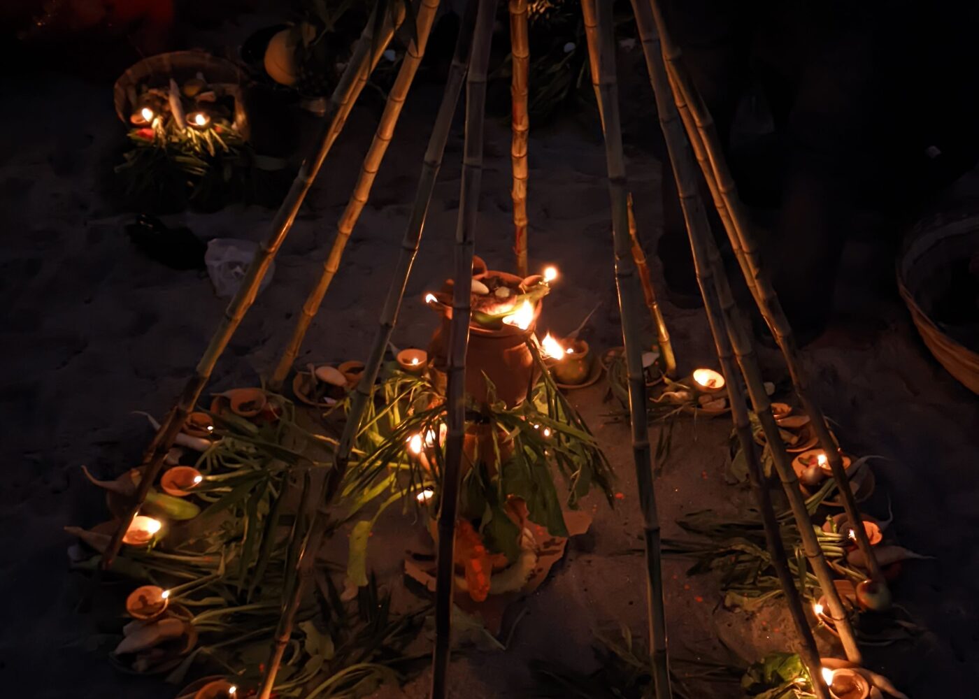 Devotees offering prayers at sunset on a riverbank during Chhath Puja